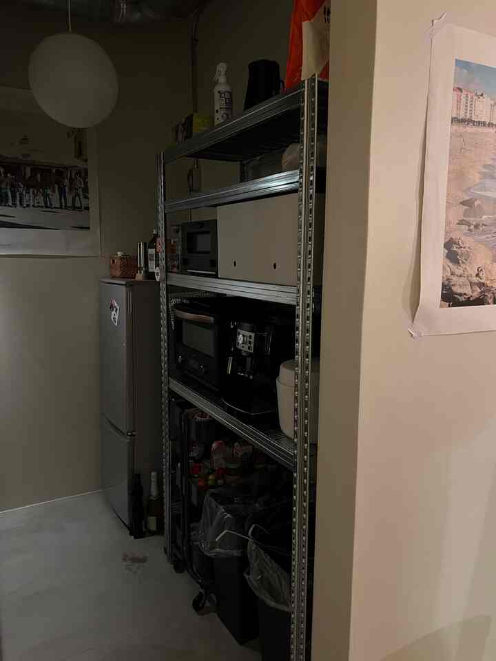 Practical kitchen space with white walls, narrow layout, silver metal shelving, and a refrigerator