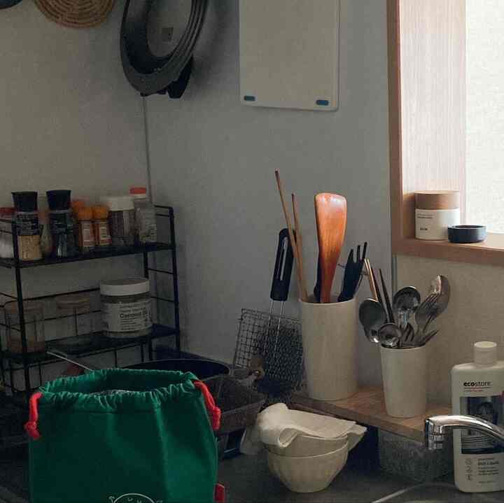 ナチュラルな色調の小さなキッチン、木製調理器具とスパイスラックが配置されたコンパクトな一人暮らしの空間