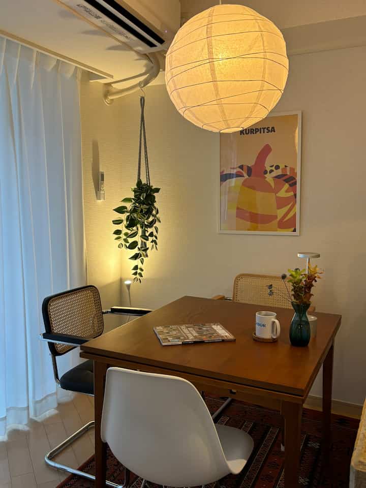 温かみのあるナチュラルカラーのダイニング、木製のダイニングテーブルとラタンチェアが配置されたヴィンテージ感のある空間