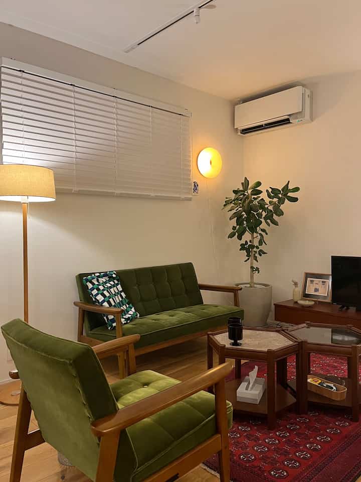Cozy living room featuring natural wood tones and green furniture, warm indirect lighting creating a soothing ambiance