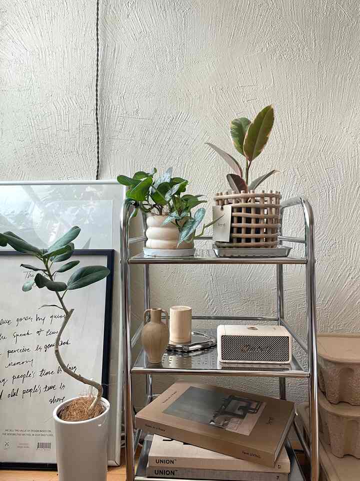 シルバーのスチールラックとベージュトーンの小物、植物が配置された落ち着いた1LDKコーナーインテリア