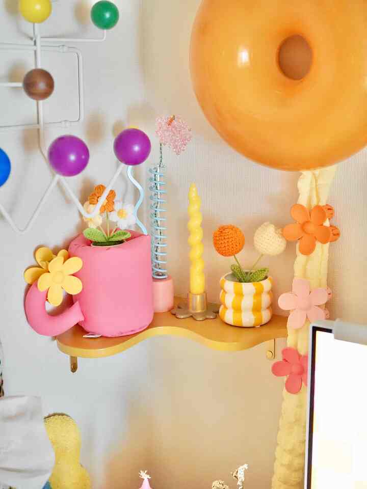 Yellow and white toned corner wall shelf featuring candles, vases and decorative objets in a cozy space