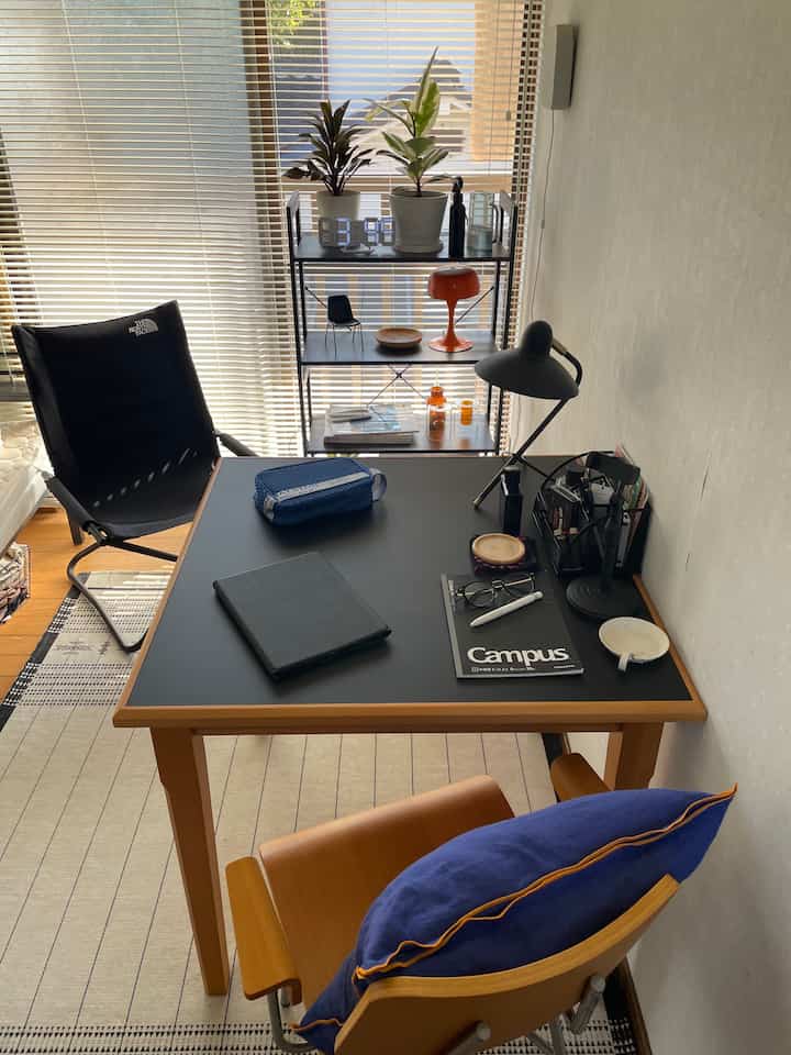 黒いテーブルトップにデスク用品と木目調の椅子が配置されたミッドセンチュリーモダンスタイルのダイニングルームの雰囲気ある空間