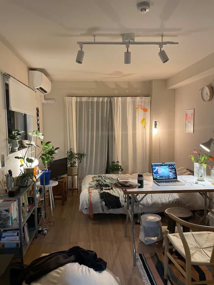 暖かみのある木目調の床と白い壁の、1人暮らし向けベッドとデスクが配置された居心地の良い部屋