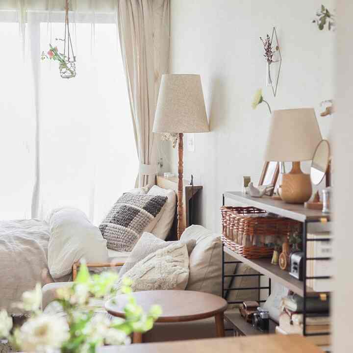 明るいベージュと木目調のワンルームリビング、クッションとフロアランプが配置された雰囲気のあるナチュラルモダンな空間