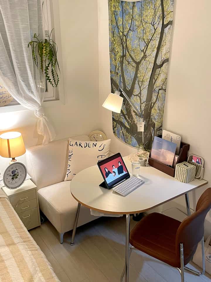 White and brown toned small home office space featuring a compact sofa and table lamps in a cozy single household room
