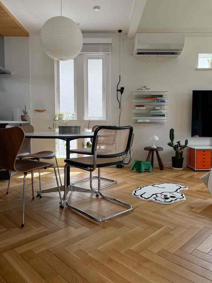 ナチュラルな木目調の床と白い壁が特徴のモダンなホームオフィス。デスクとペンダントライトが配置された明るく快適な作業空間