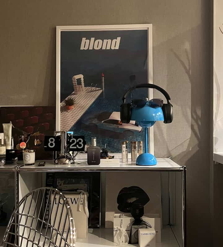 ブルーとシルバーのトーンで統一されたモダンなリビング、ヘッドホンスタンドと化粧品が置かれたメタルシェルフのある雰囲気のあるインテリア