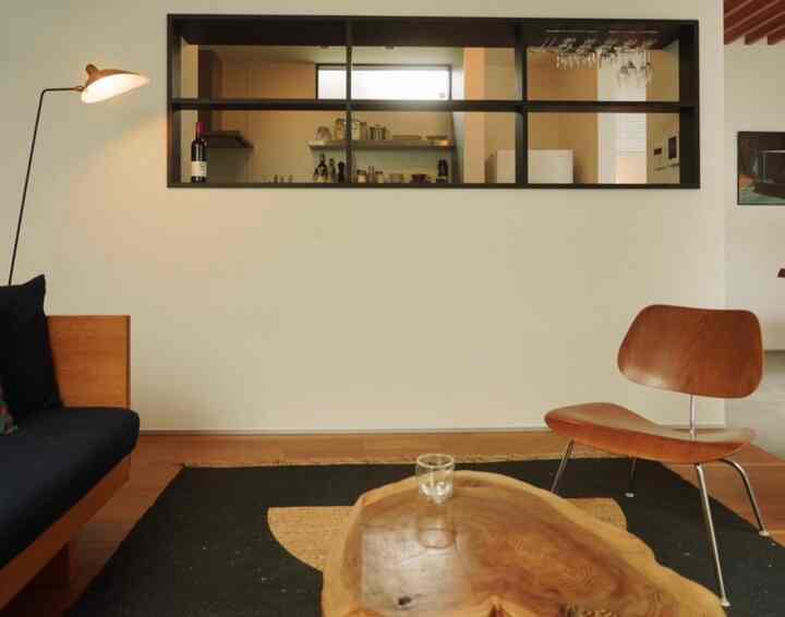 木目調と黒を基調としたリビング空間、ミッドセンチュリーモダンのラウンジチェアとソファ、フロアランプが配置された温かみのあるインテリア