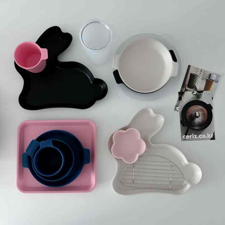 白い背景の上にピンク、黒、ネイビーの子供用キャンプ食器セットが配置された清潔感のあるキッチンテーブル