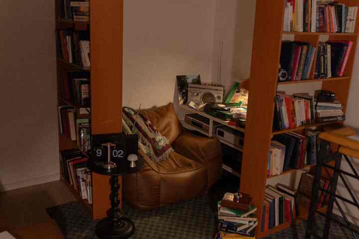 暖かいブラウン調の居心地の良い書斎、中央に大きなレザーのビーズクッションソファと両側に本棚が配置された空間