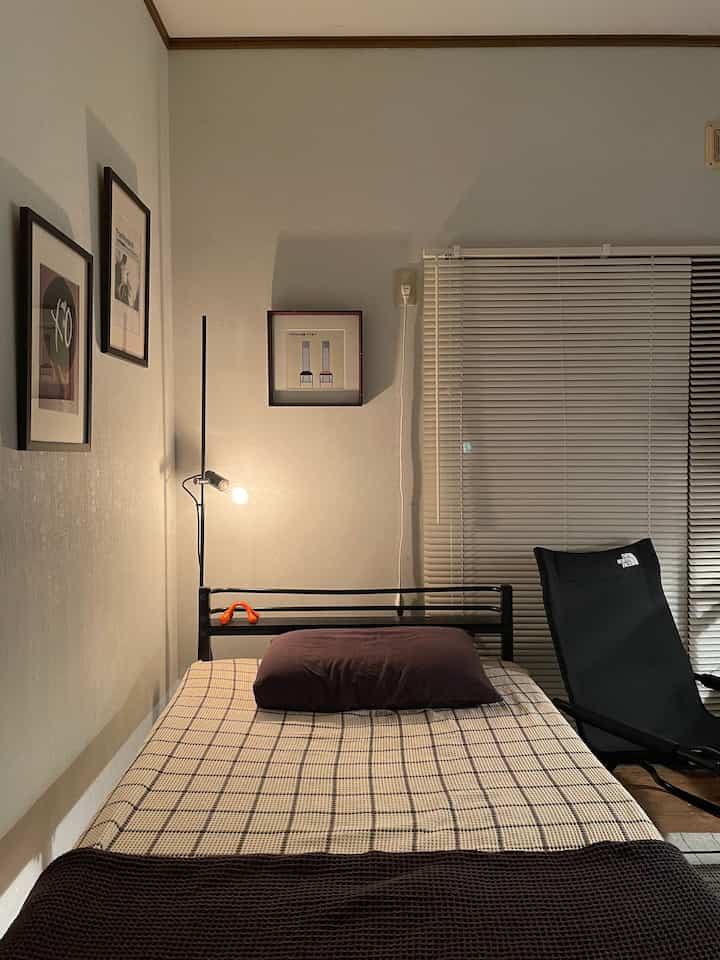 Beige and brown toned bedroom featuring single bed and floor lamp with modern atmosphere