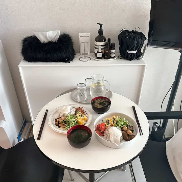 白黒のトーンでまとめられたミニマルな小さなリビング、丸いダイニングテーブルと食器が印象的な空間