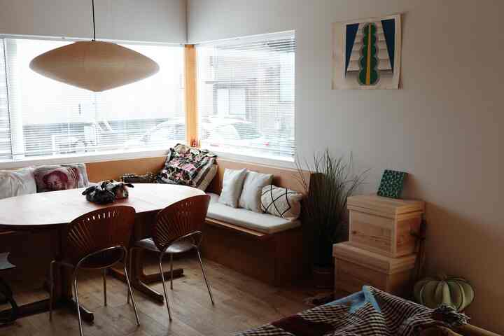 白と茶色のトーンのヴィンテージ感あふれるダイニングルーム、木製の食卓とベンチ、ペンダントライトが調和した印象的な空間