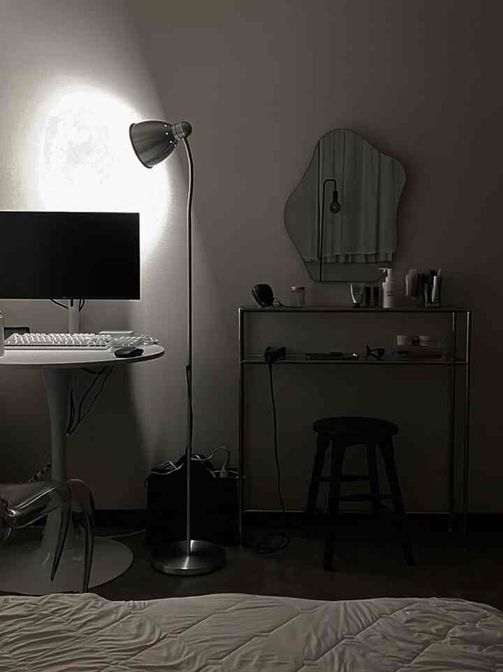 白と銀色のトーンの寝室、ステンレス製コンソールとデスク、フロアランプが配置されたミニマルな雰囲気のインテリア