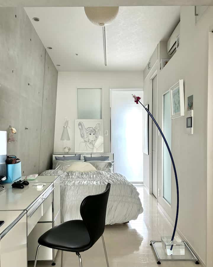 白を基調とした縦長の寝室、中央にベッドとセブンチェアを配置したモダンな雰囲気のインテリア