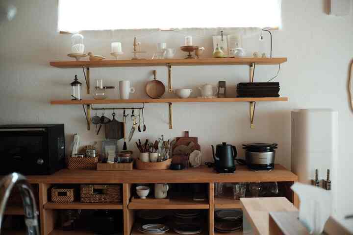 ナチュラルな木目調と白い壁が調和するキッチン、さまざまな収納アイデアが詰まった飾り棚と調理器具のある雰囲気のあるインテリア