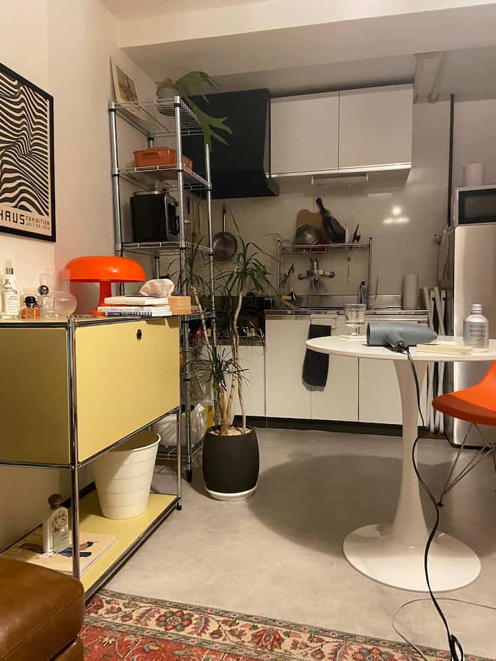 Yellow and orange accents highlight a single household 1DK kitchen-living area with mid-century modern style, creating a cozy interior