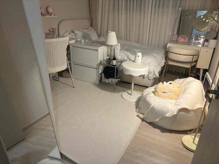 白を基調としたコンパクトな学生部屋、ベッドやデスク、ビーンバッグチェアが配置されたモダンで落ち着いたインテリア