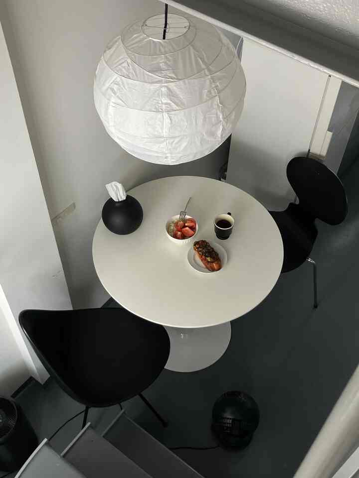 白と黒のダイニング、丸いテーブルとフリッツハンセンの椅子が配置されたシンプルなカフェ風インテリア