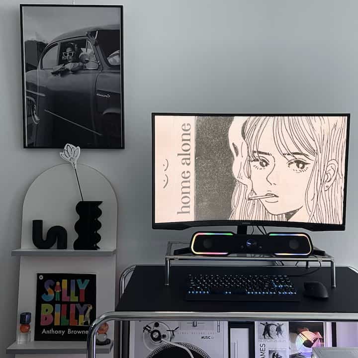 Charcoal and white toned home office featuring a black desk and monitor stand in a Mid-Century Modern style interior
