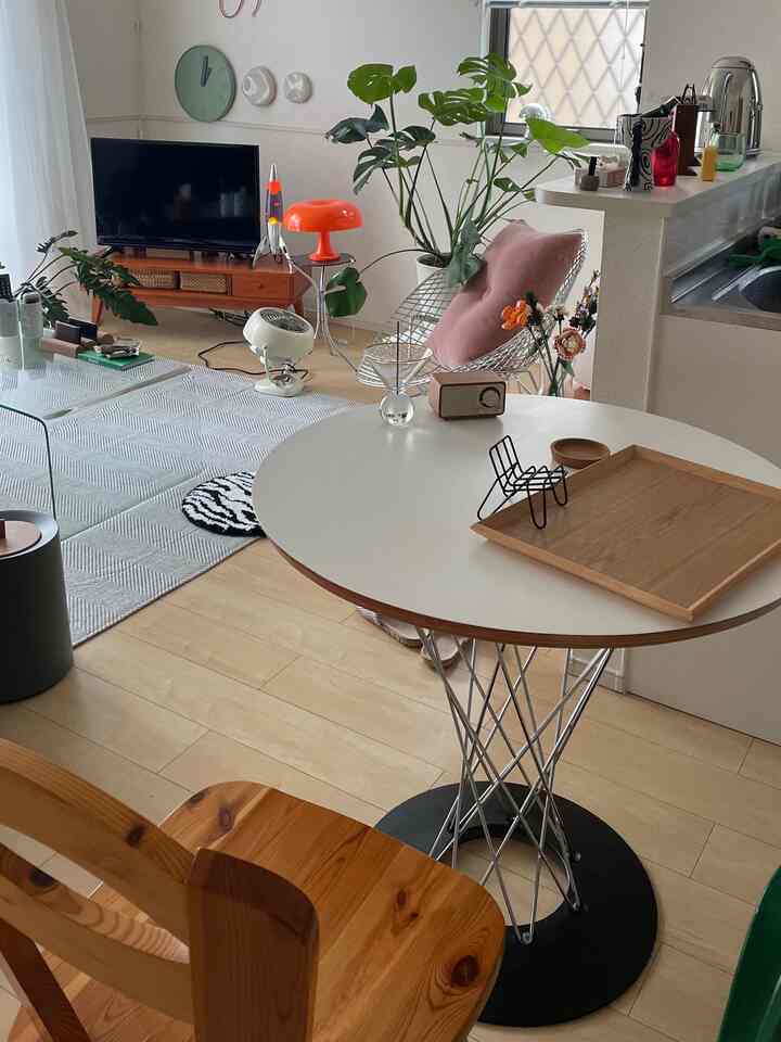 A mid-century modern dining room with soft wood tones and white accents, featuring green plants and cozy decor elements