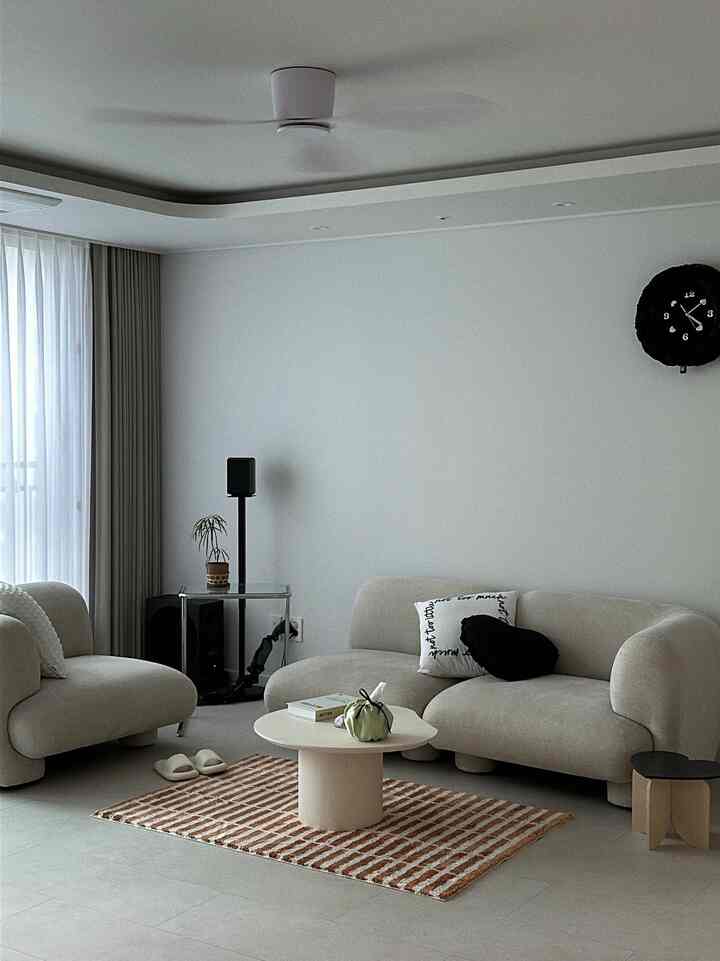 白とベージュのトーンが調和したリビング、曲線のソファとラグが配置された自然なモダンスタイルのインテリア