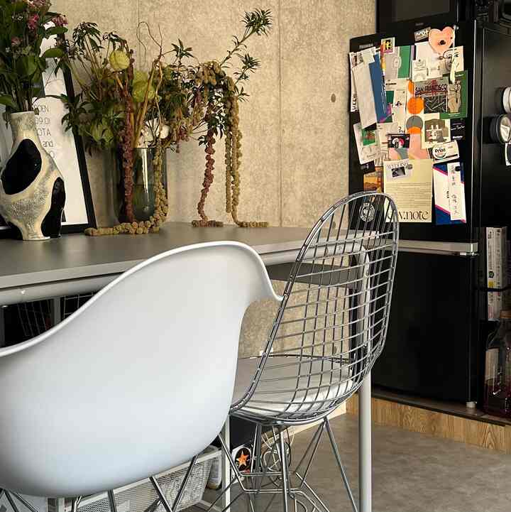 白と黒が調和するモダンなキッチン空間、グレーのテーブルと椅子が配置され、花瓶に植物が飾られている