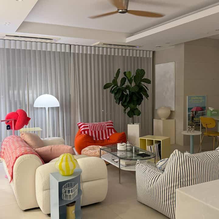 Colorful living room dominated by white and orange tones featuring bean bag, sofa, and floor lamp in a trendy layout