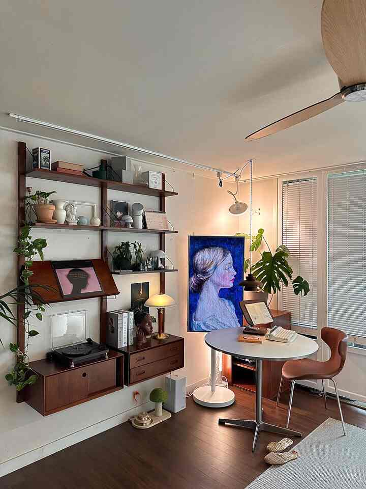 Natural wood tone vintage living room featuring a round reading table and lush green plants in a cozy setting
