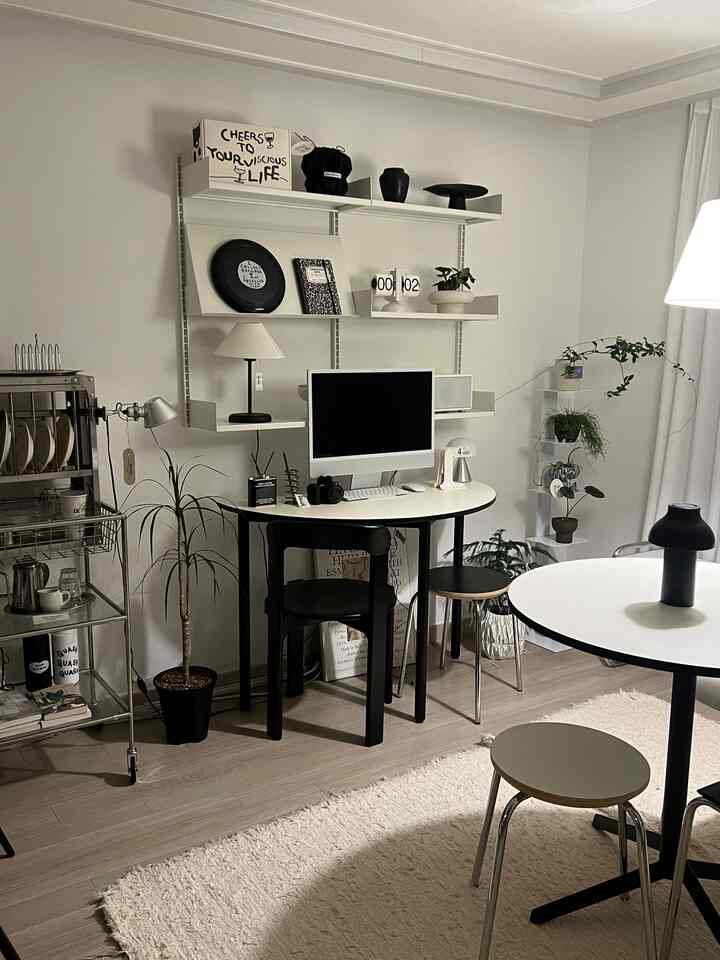 Monotone black and white living room featuring round table, desk, and plants in a modern setting