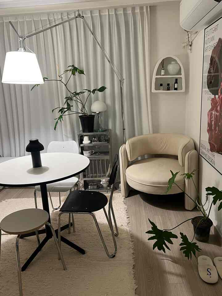 White and beige toned living and dining room featuring simple furniture and a floor lamp in a modern natural space