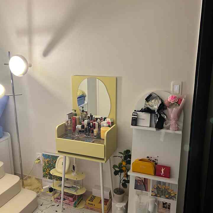 Small room in white and yellow tones featuring a vanity with mirror and organized shelving creating a cozy atmosphere