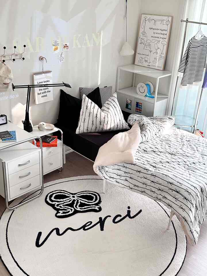 Natural modern small bedroom in white and black tones featuring a bed, desk, and round rug arranged for a single occupant