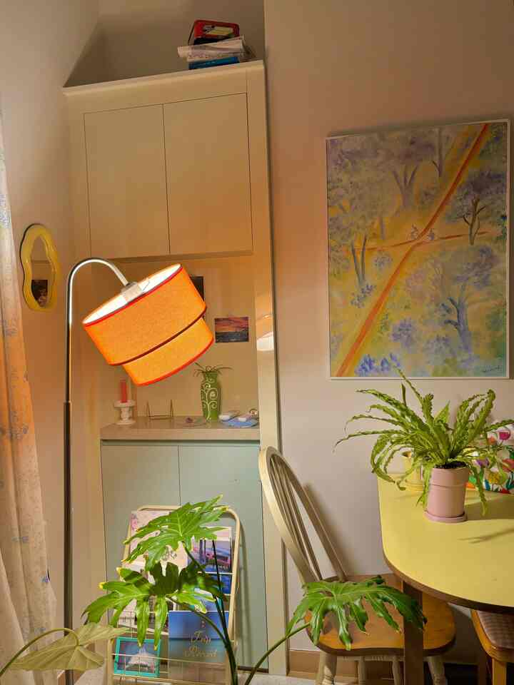 A natural vintage style living and dining room with warm orange lighting and a yellow dining table