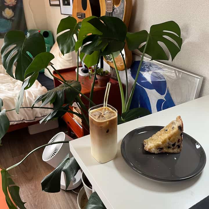 緑豊かな観葉植物と白いテーブルにアイスコーヒーとケーキが置かれた、居心地の良い8畳の寝室インテリア