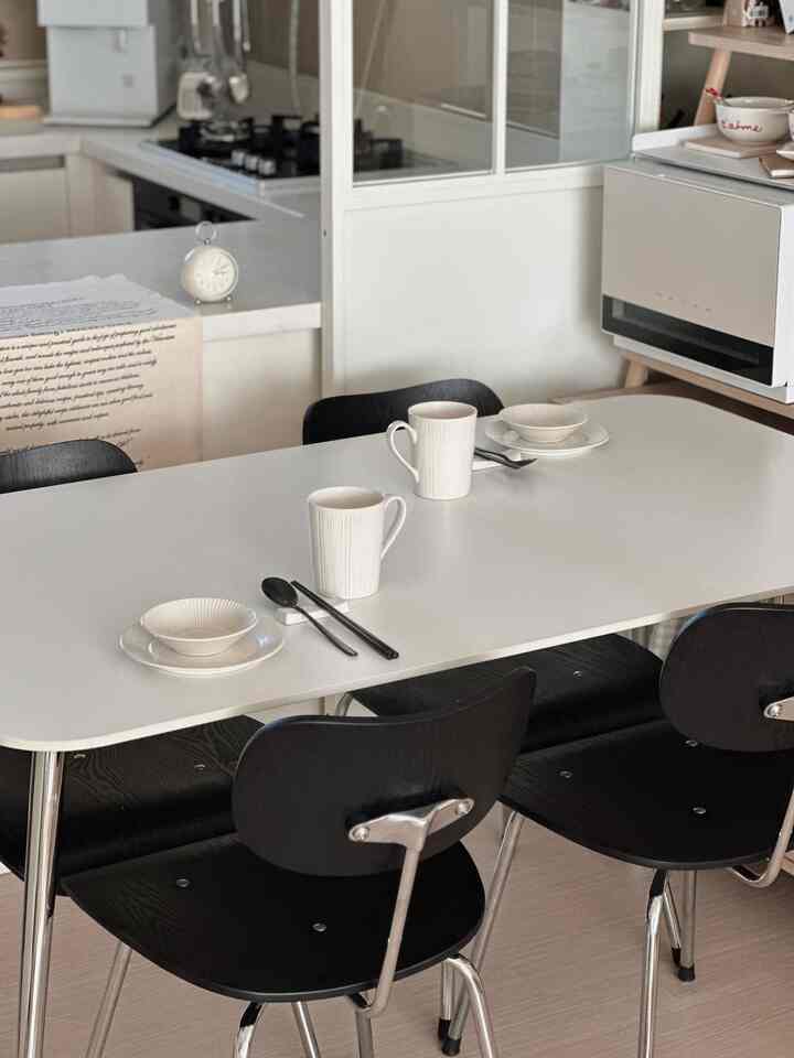 White and black toned kitchen and dining area featuring a two-person dining table set with a clean, minimal atmosphere