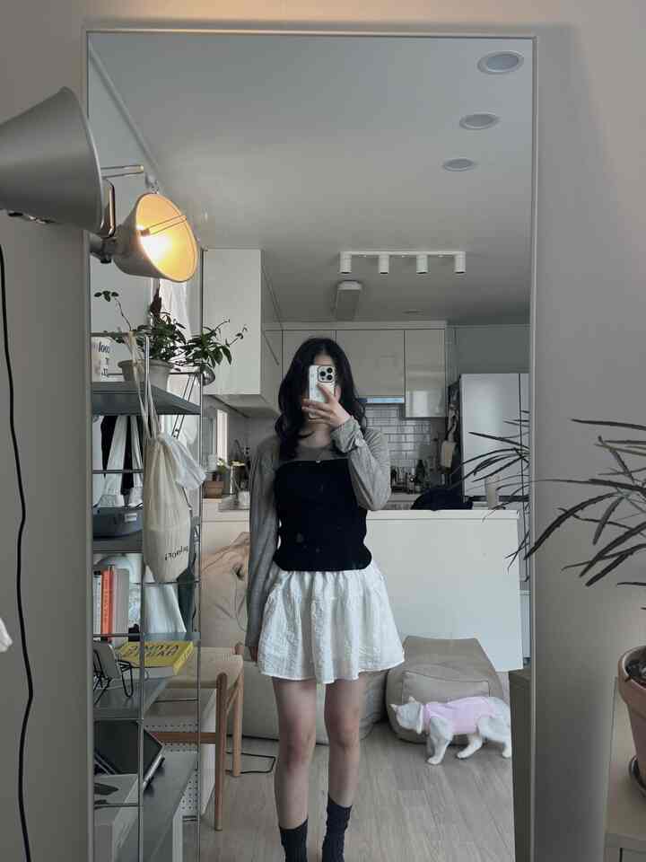 ホワイトとベージュのトーンでまとめられたミニマルな一人暮らしの空間、大型の全身鏡とビーンバッグ、フロアランプが配置された静かなインテリア