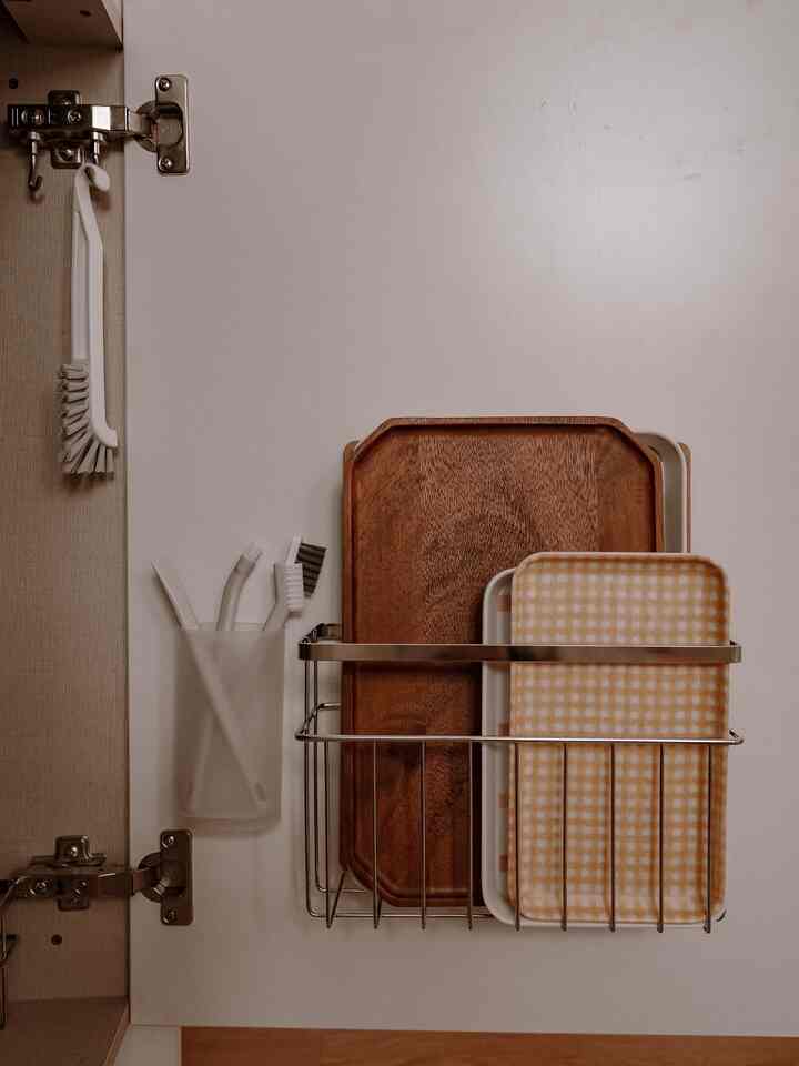 White interior kitchen cabinet featuring wood and melamine trays with neatly stored kitchen brushes