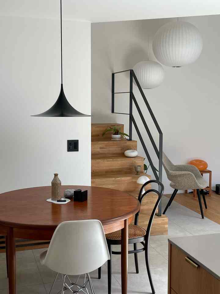 白と木目調の調和があるモダンなダイニング、丸いダイニングテーブルと多様な椅子が配置された印象的な空間