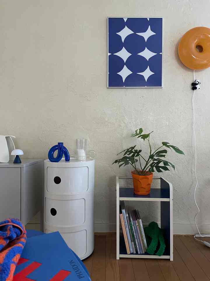 ホワイトの壁とブルーの棚、オレンジ色の鉢に置かれた緑の植物がある洗練されたミッドセンチュリーモダンのインテリア