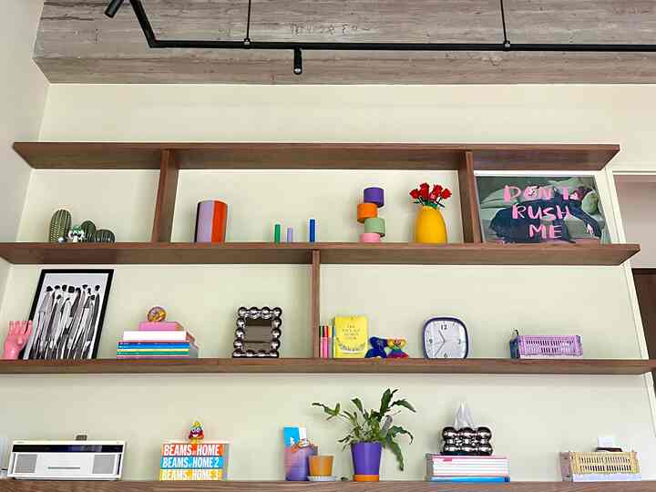 A living room with white walls and wood-tone shelves featuring colorful decor items artistically displayed