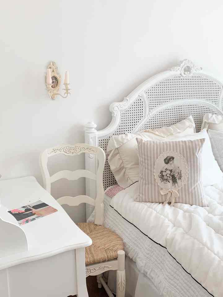 白を基調とした寝室、アンティーク家具と整ったクッションが配置された落ち着いた雰囲気のインテリア