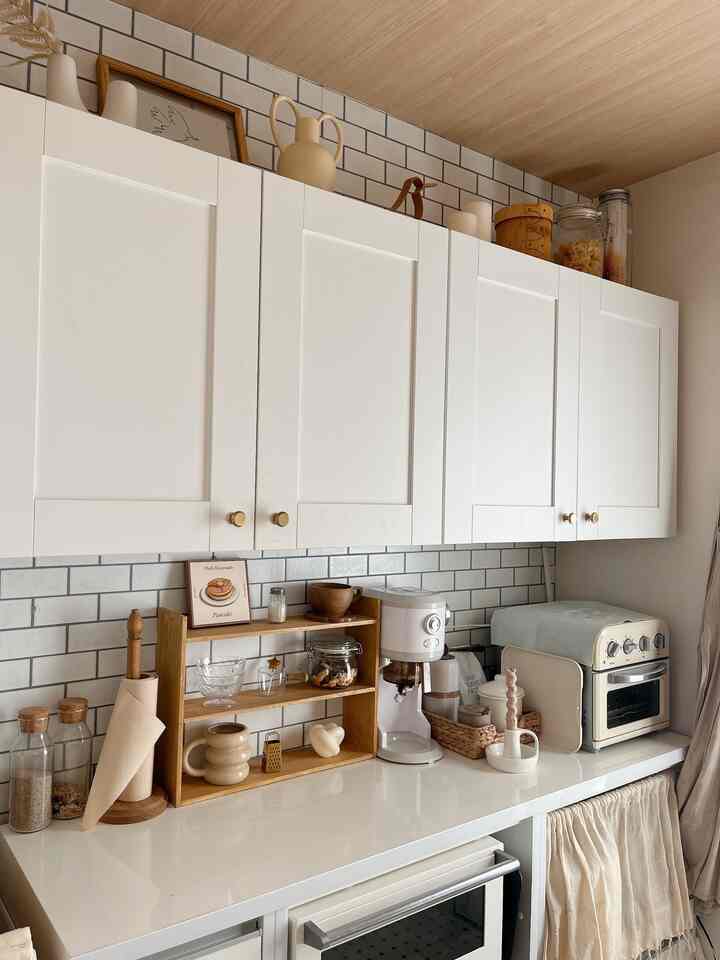 白と木目調が調和した明るく清潔感のあるキッチン、北欧スタイルのインテリアにコーヒーマシンと多目的収納棚が配置された空間