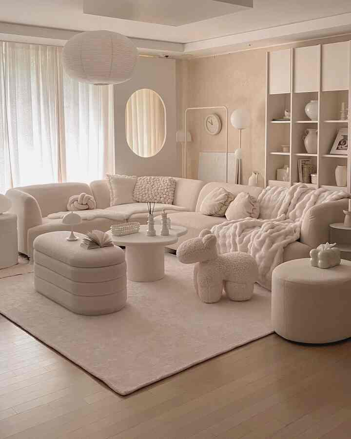 アイボリーのトーンのリビング、ブークレソファとホワイトのリビングテーブル、短毛ラグ、スツールが配置された温かみのある高級感あふれるインテリア