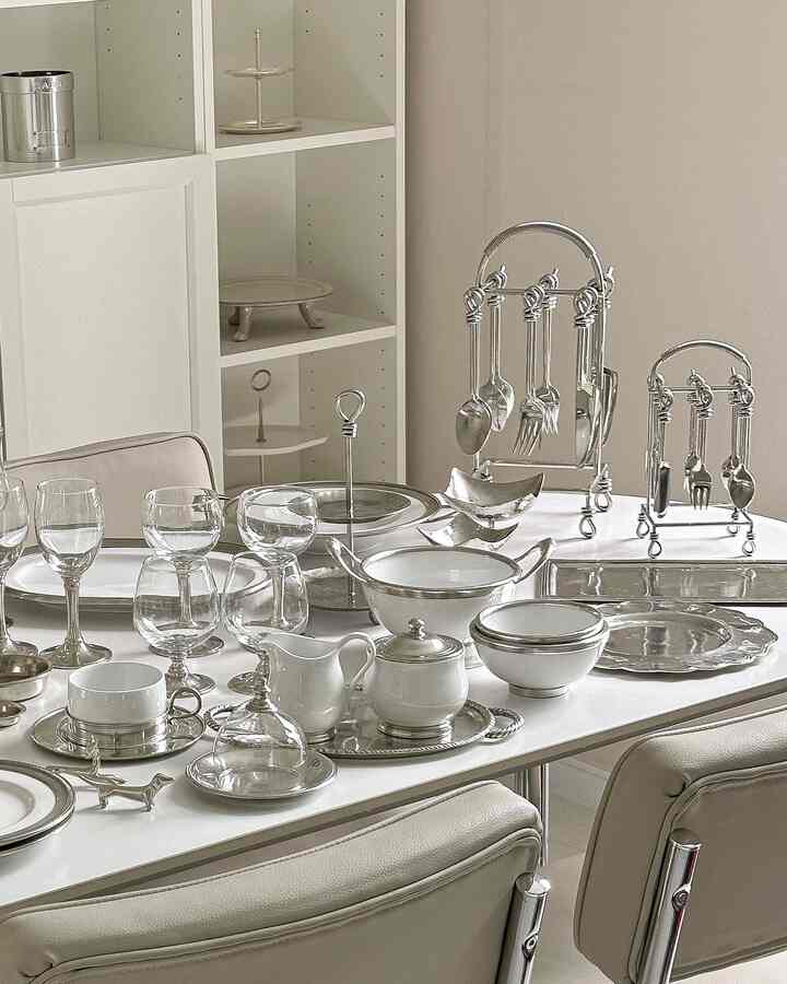 白とシルバーの色調のダイニング、洗練されたカトラリーとワイングラスが配置されたモダンな食卓の印象的な空間