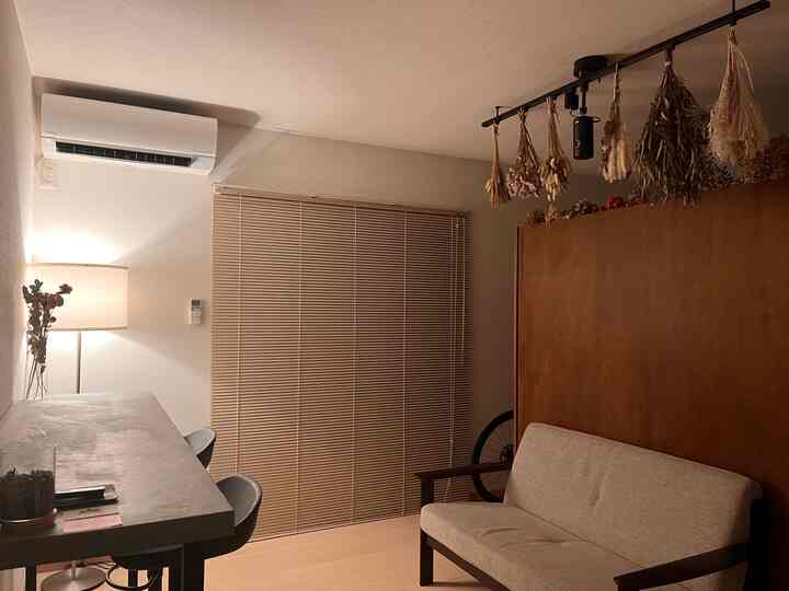 Natural wood tones and white walls in a 1K living space featuring dried flowers and cozy lighting