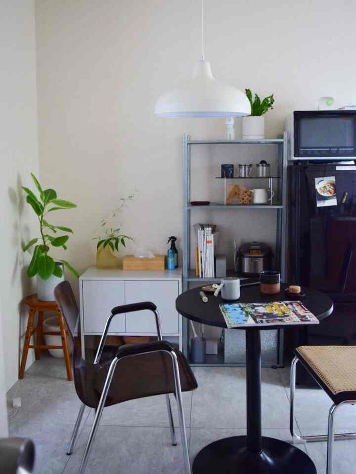 白と黒の色調のダイニング、丸テーブルとモダンチェア、棚とキャビネットが配置された清潔感のある空間