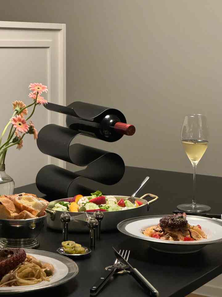 Gray and black toned home dining room featuring a wine rack and various dishes on a sleek dining table