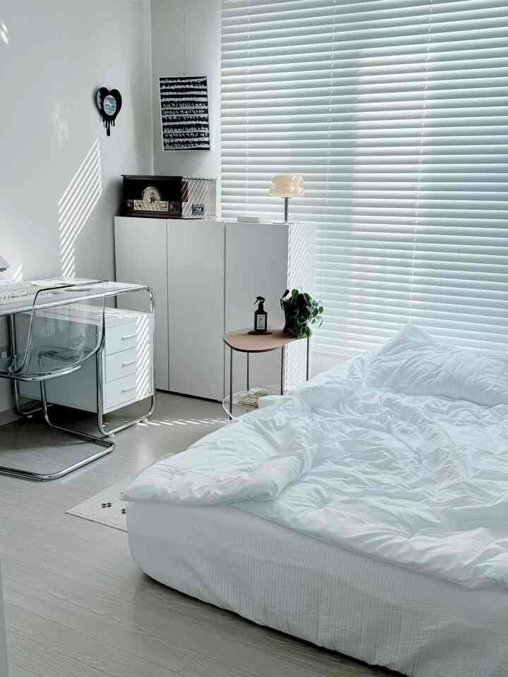 White and gray toned bedroom featuring a white bed, desk, and window blinds in a modern and clean atmosphere